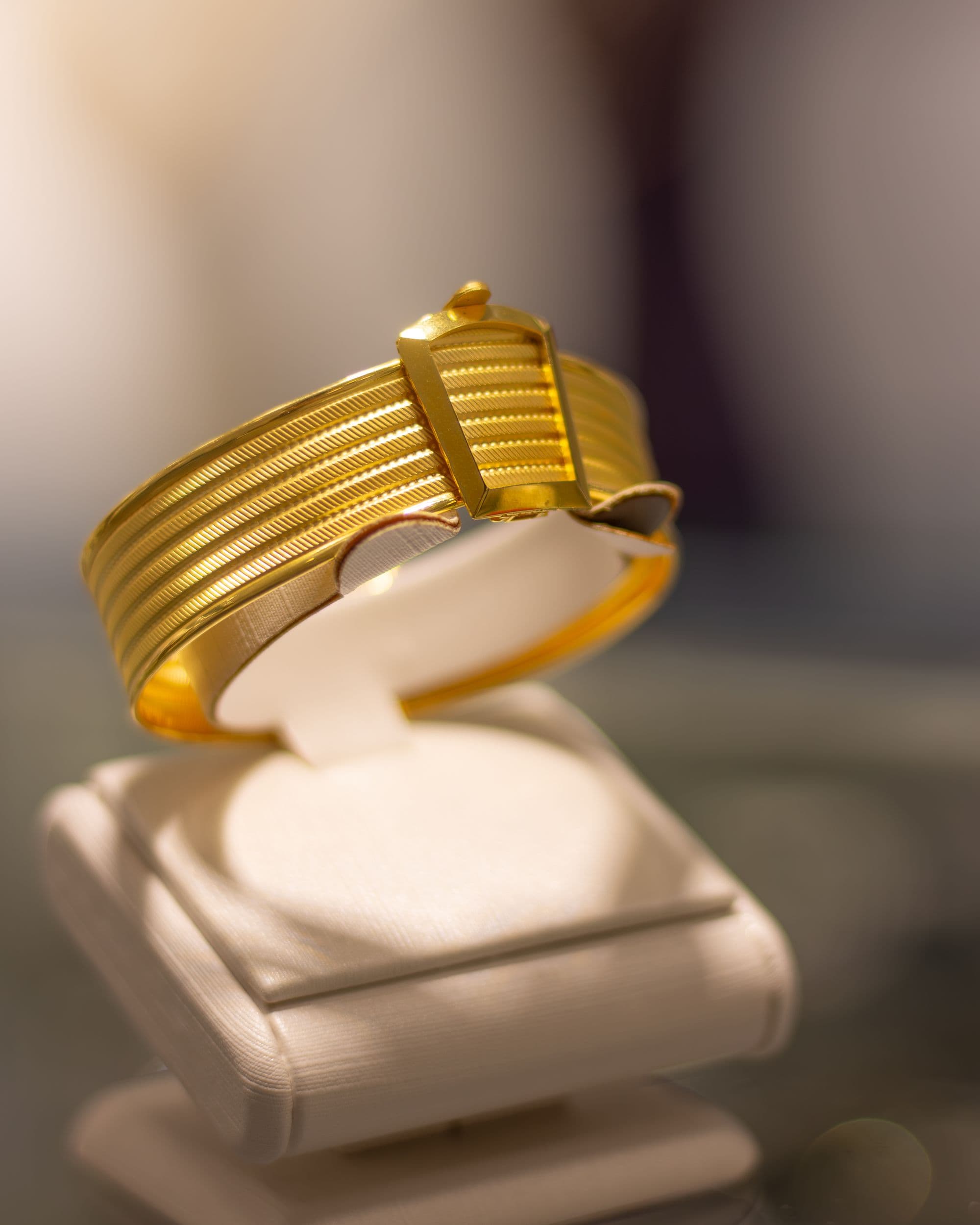 Ribbed 18K gold cuff bracelet on a cream display